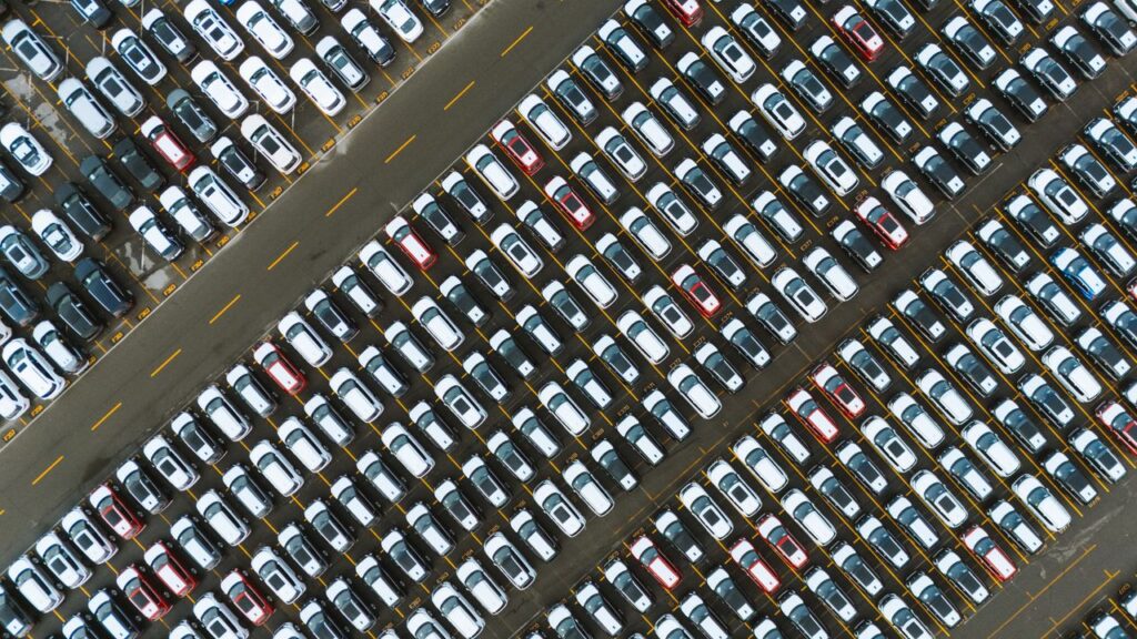 Aerial perspective of neatly parked cars in a large parking lot.