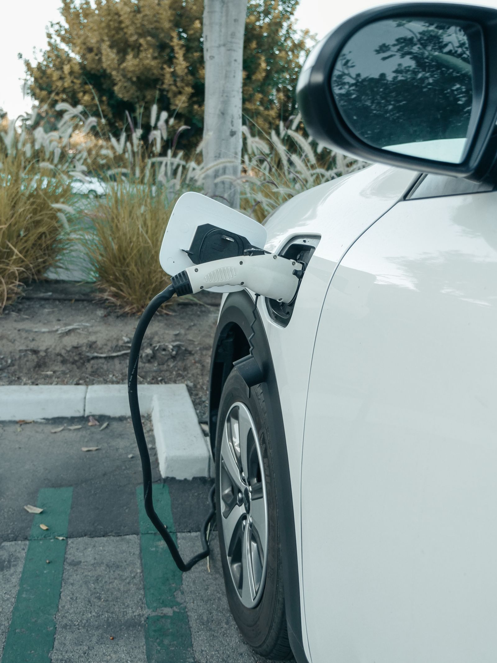 White electric car plugged into a charger at an outdoor area