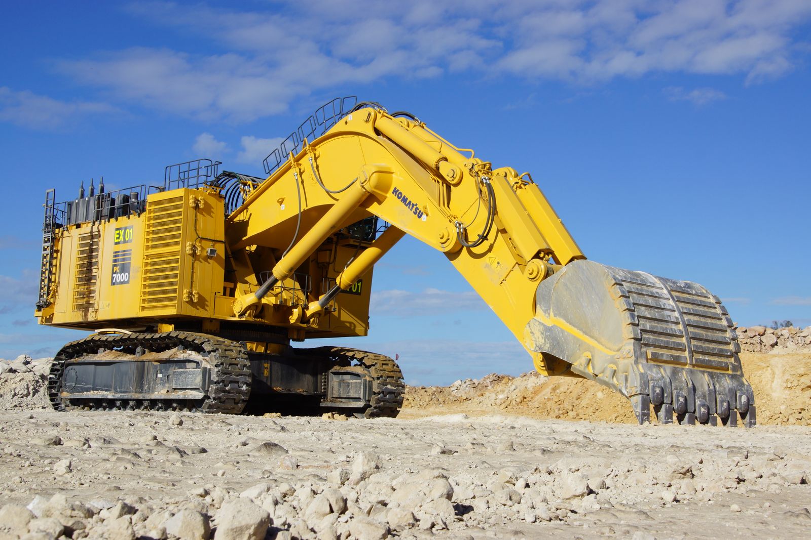Yellow excavator at an open construction site under a blue sky