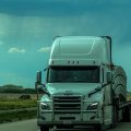 White semi truck travelling on a highway under a dramatic sky